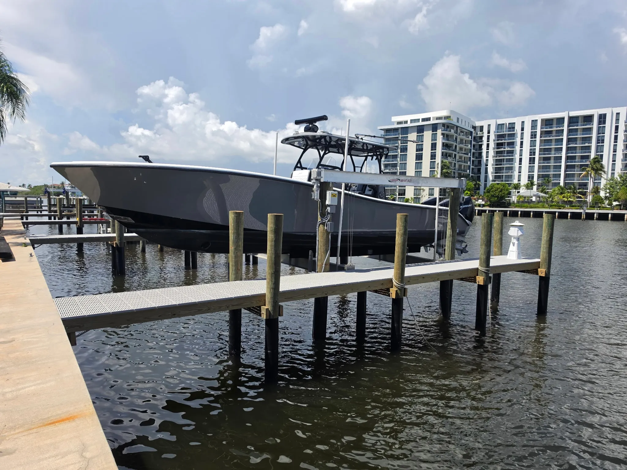 Center-console boat raised on a Hurricane boat lift at a new dock with grated decking, built by Florida Marine Builders
