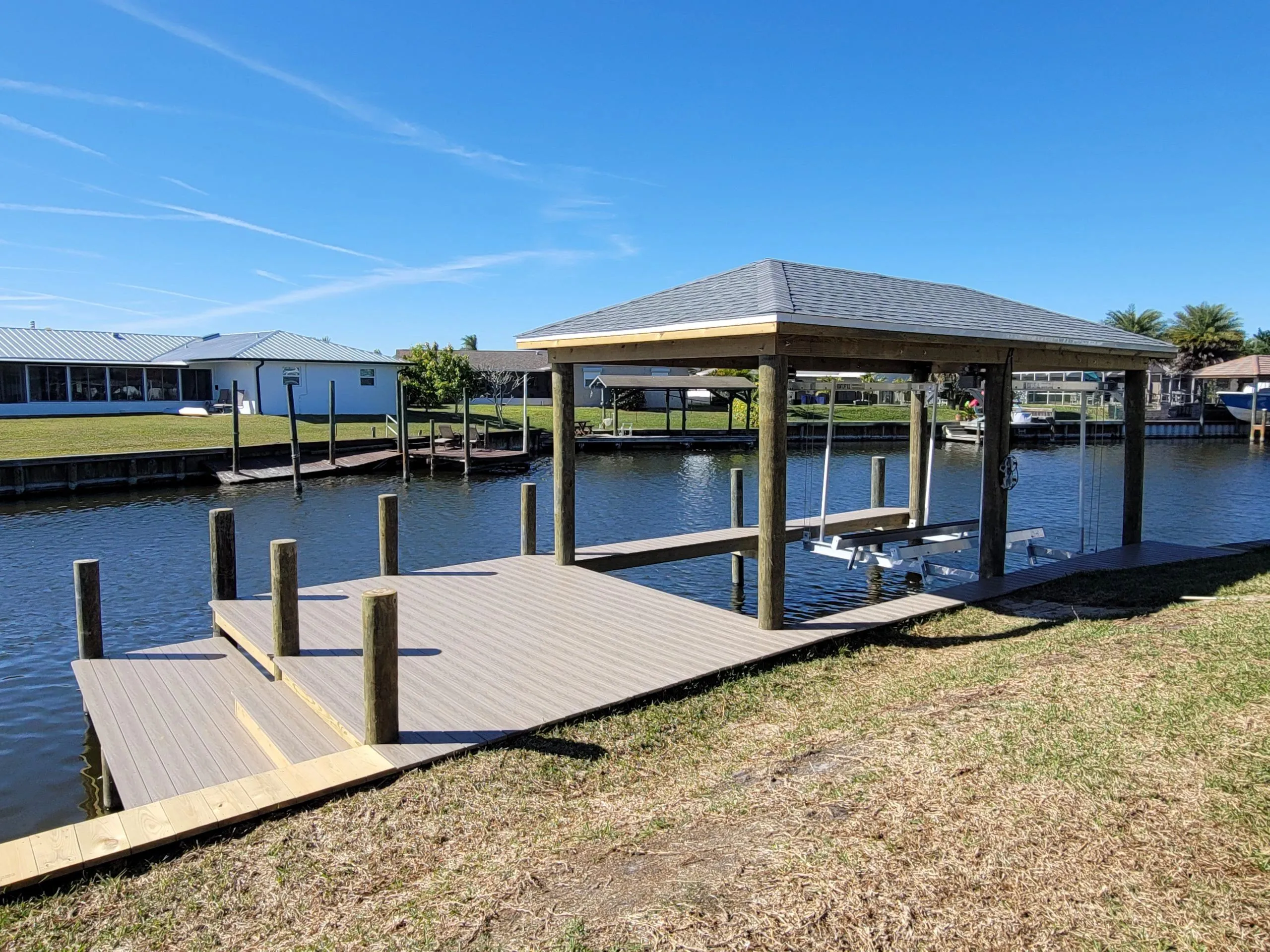 Covered boathouse with hip roof and boat lift over composite decking on a residential canal