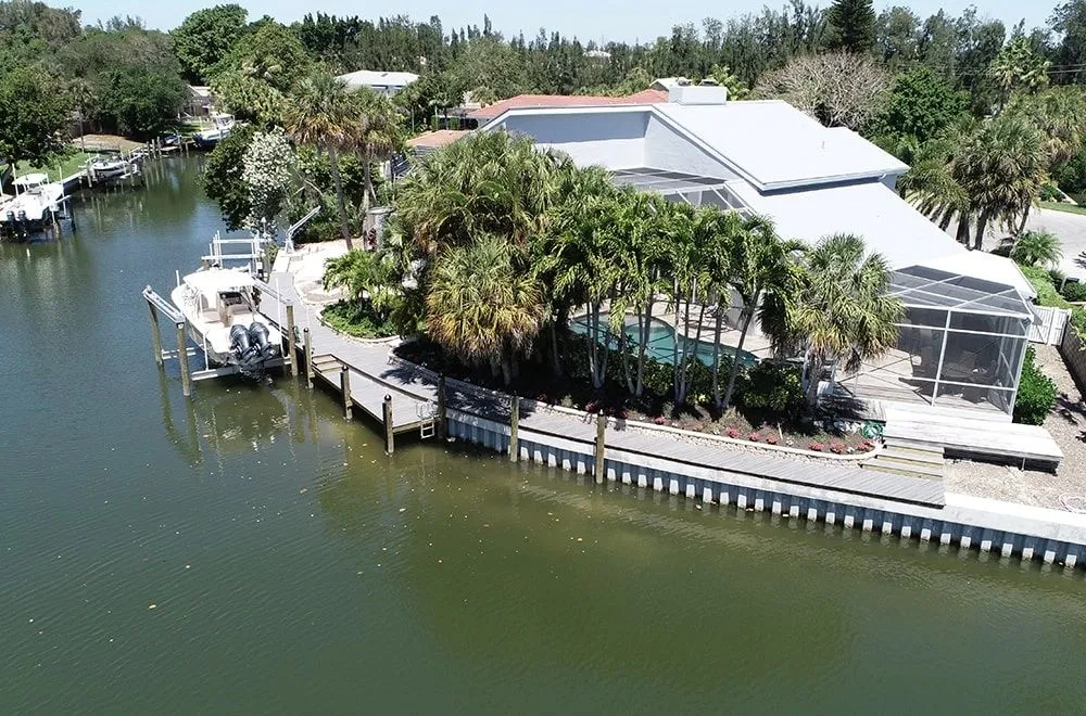Aerial view of a completed seawall with concrete cap and dock walkway protecting a landscaped waterfront property
