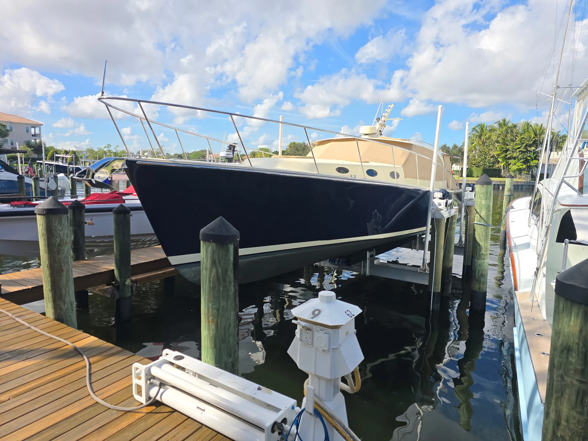 Dark-hulled yacht raised on a Hi-Tide boat lift beside a hardwood dock built by Florida Marine Builders